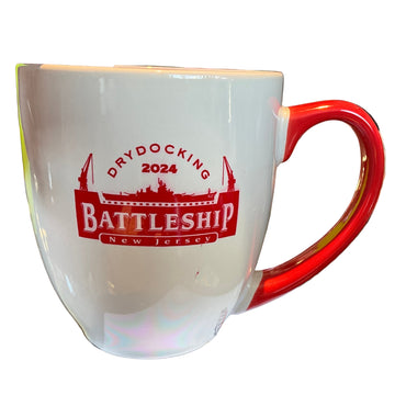 White mug with red handle and 'Dry docking 2024 Battleship New Jersey' text on a table.