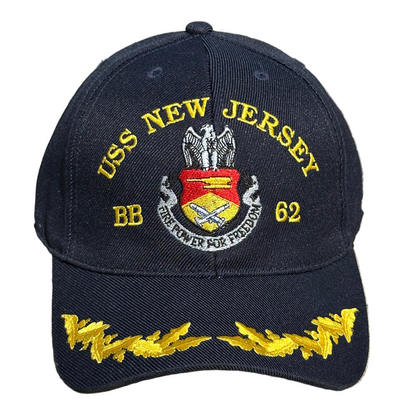 Navy blue cap with USS New Jersey and yellow text on a concrete surface