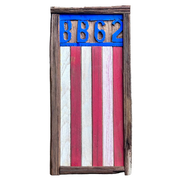 Wooden plaque with American flag design and 'BB62' text on a concrete surface