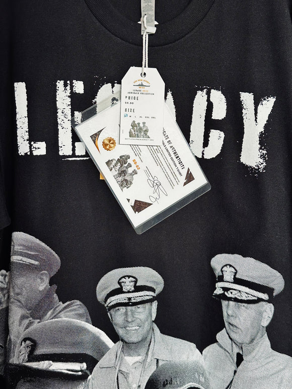 Black t-shirt with 'LEGACY' text and vintage military imagery, featuring a tag with event details. Battleship Graphic T's