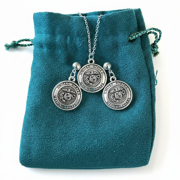 Silver necklace with three round pendants on a teal velvet bag.