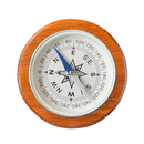 A round analog compass with a warm brown wooden frame, a white dial face, black degree markings and cardinal directions, and a blue needle pointing north.