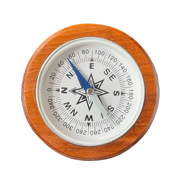 A round analog compass with a warm brown wooden frame, a white dial face, black degree markings and cardinal directions, and a blue needle pointing north.