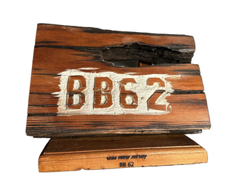 Wooden sign with 'BB62' engraved on it, placed on a metallic surface.