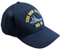 Navy blue cap with USS New Jersey BB 62 logo on a light wooden surface